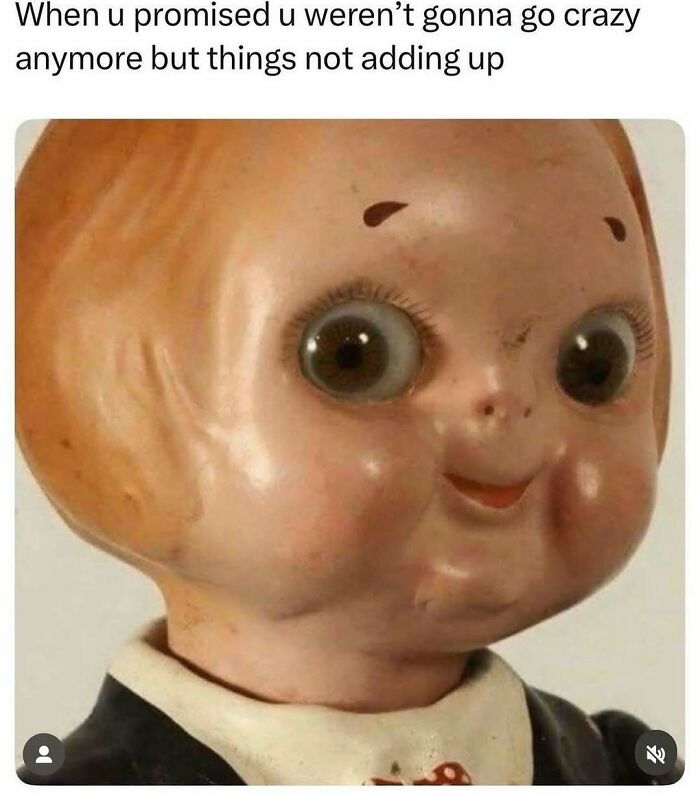 Close-up of a vintage doll’s face with wide eyes and a smile, a funny meme to handle reality with humor.