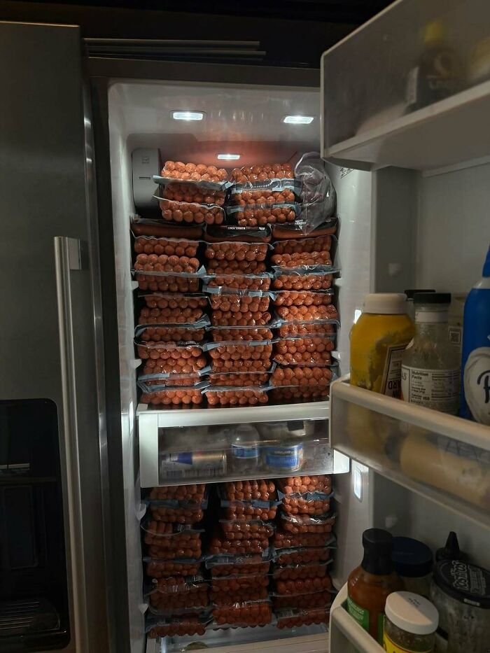 Refrigerator fully stocked with dozens of packs of hot dogs, showcasing a wild dude fridge filled to the brim.