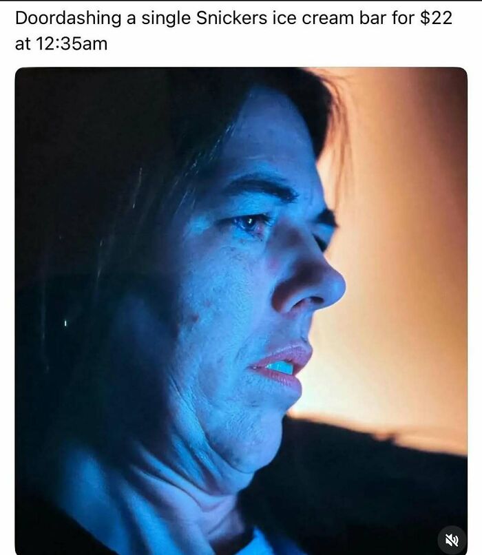 Person with a shocked expression illuminated by blue light, captioned about Doordashing a Snickers ice cream bar at night, meme humor.