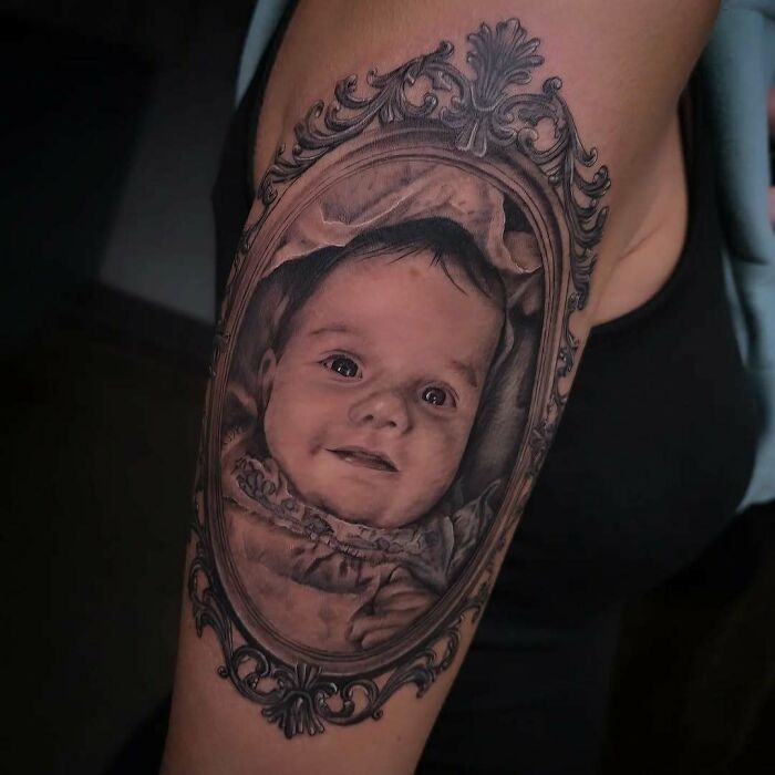 Realistic portrait tattoo of a baby framed in ornate vintage style, showcasing wholesome tattoos with meaningful ink on upper arm. Realistic portrait tattoo of a baby framed in ornate vintage style, showcasing wholesome tattoos with meaningful ink on upper arm.