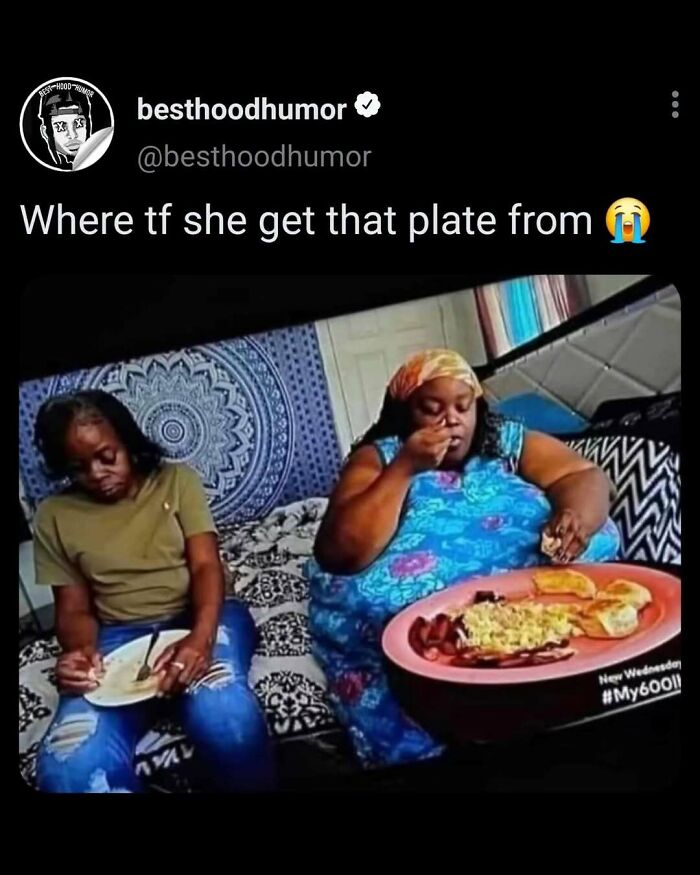 Two women sitting on a bed eating with one holding an oversized plate in a funny meme post from besthoodhumor.
