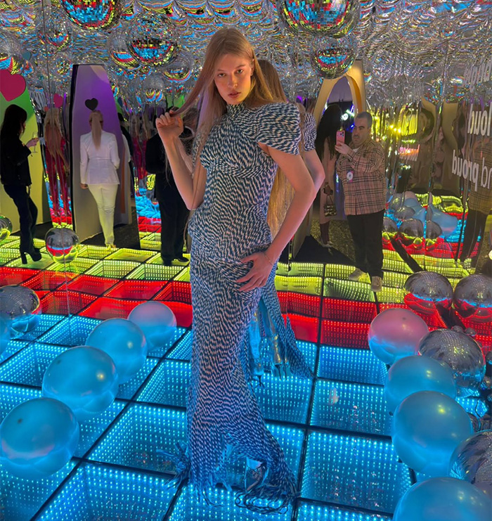 Young woman posing on colorful LED floor surrounded by reflective balloons in a mirrored room, evoking tragic mental illness theme. Young woman posing on colorful LED floor surrounded by reflective balloons in a mirrored room, evoking tragic mental illness theme.
