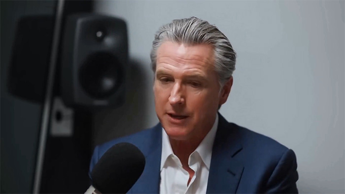 Man in navy suit speaking into microphone during a podcast, discussing tragic mental illness and public reaction online. Man in navy suit speaking into microphone during a podcast, discussing tragic mental illness and public reaction online.