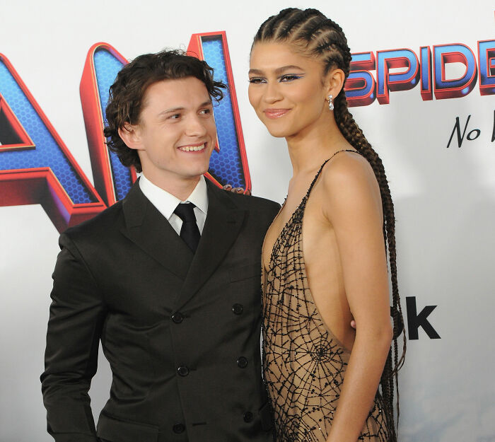 Robert Pattinson and Zendaya smiling together at a red carpet event, promoting viral engagement ad.