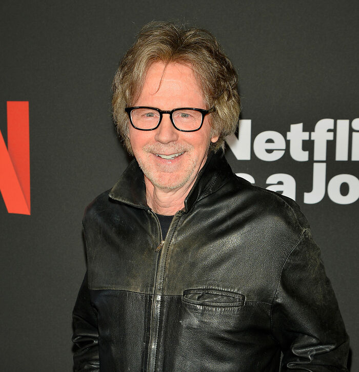 Man with glasses in a black leather jacket smiling at a Netflix event, related to banned stars from the Tonight Show topic. Man with glasses in a black leather jacket smiling at a Netflix event, related to banned stars from the Tonight Show topic.