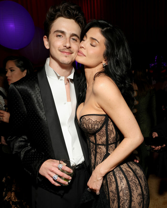 Timothée Chalamet in a black tuxedo and Kylie Jenner in a lace dress posing together at a red carpet event. Timothée Chalamet in a black tuxedo and Kylie Jenner in a lace dress posing together at a red carpet event.