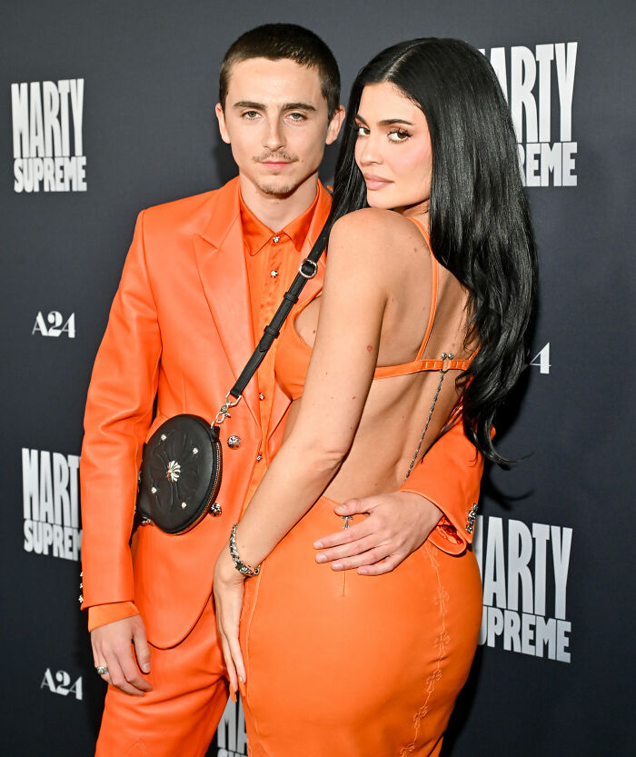 Timothée Chalamet and Kylie Jenner posing together on red carpet, both wearing coordinated orange outfits. Timothée Chalamet and Kylie Jenner posing together on red carpet, both wearing coordinated orange outfits.