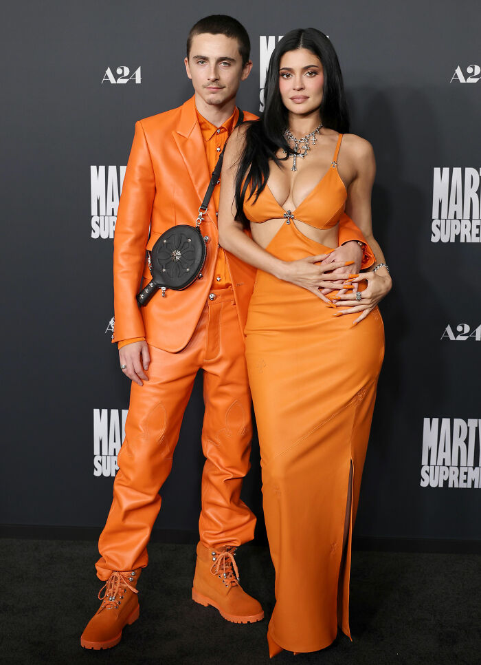 Timothée Chalamet and Kylie Jenner on the red carpet wearing matching orange outfits with a unique fashion detail. Timothée Chalamet and Kylie Jenner on the red carpet wearing matching orange outfits with a unique fashion detail.