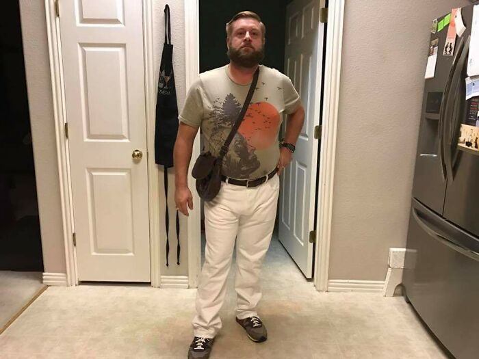 Man standing in casual outfit in a kitchen, showcasing relaxed and fun sibling life moments indoors.