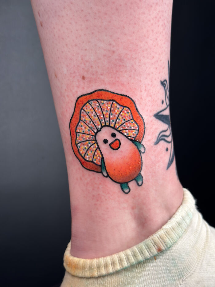 Psychedelic tattoo of a colorful smiling mushroom on ankle with vivid orange and green hues and decorative patterns. Psychedelic tattoo of a colorful smiling mushroom on ankle with vivid orange and green hues and decorative patterns.