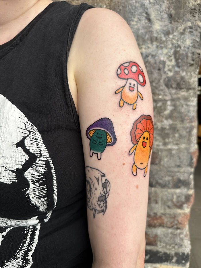 Colorful psychedelic tattoos of smiling mushrooms on a person's upper arm showcasing unique vibrant designs. Colorful psychedelic tattoos of smiling mushrooms on a person's upper arm showcasing unique vibrant designs.