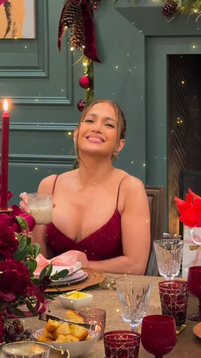 Jennifer Lopez smiling at a Christmas dinner table with holiday decorations and people calling out her Photoshop skills.