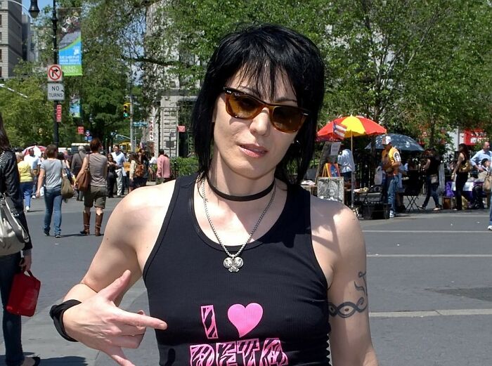 Person wearing sunglasses and black tank top outdoors, representing a once famous regular job in an urban setting.