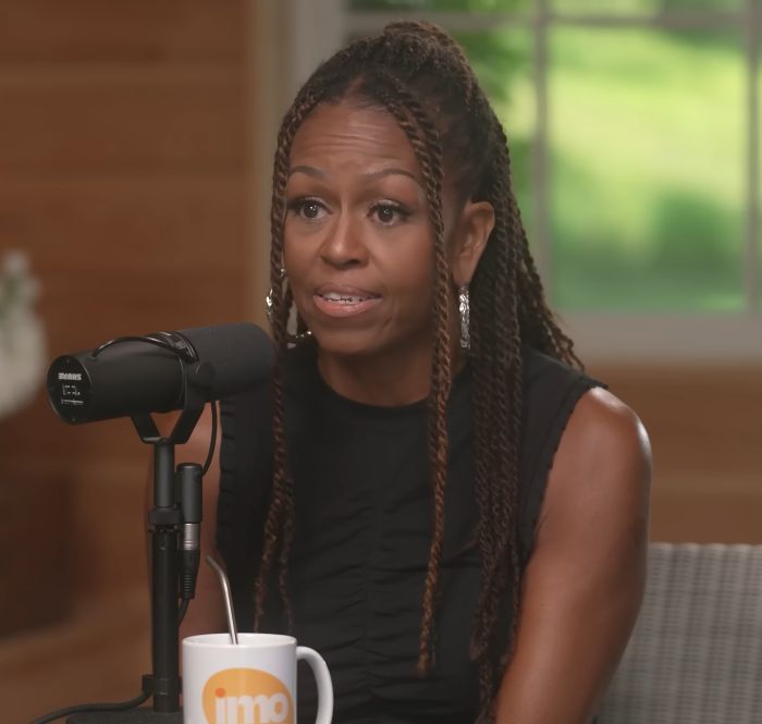 Michelle Obama speaking into a microphone during an interview, showcasing her bold new makeup look. Michelle Obama speaking into a microphone during an interview, showcasing her bold new makeup look.