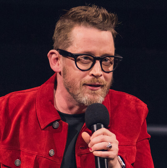 Macaulay Culkin speaking into a microphone, wearing glasses and a red jacket, addressing Home Alone Kevin’s dad job theory. Macaulay Culkin speaking into a microphone, wearing glasses and a red jacket, addressing Home Alone Kevin’s dad job theory.