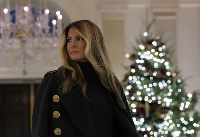 Melania Trump standing indoors near a decorated Christmas tree, related to her new Christmas ornament controversy. Melania Trump standing indoors near a decorated Christmas tree, related to her new Christmas ornament controversy.