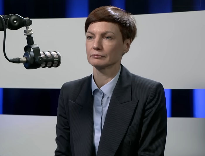 Person in a dark suit speaking into a microphone during an interview about Lithuania lawmaker’s cat consent for broadcaster firing. Person in a dark suit speaking into a microphone during an interview about Lithuania lawmaker’s cat consent for broadcaster firing.