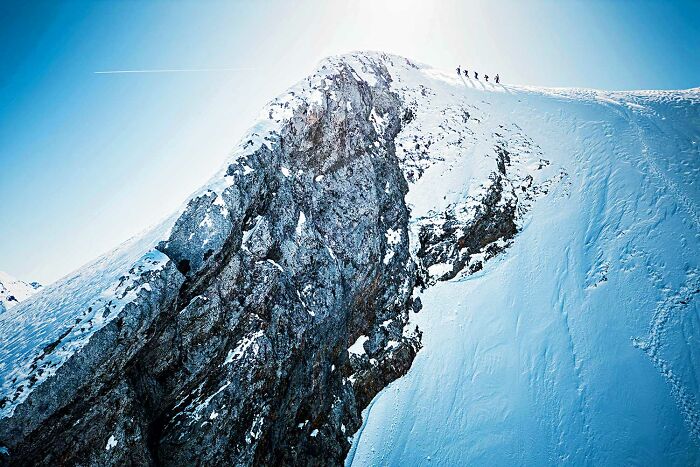 Climbers hiking along a snowy mountain ridge in a stunning scene from the 2025 National Wildlife Photo Contest.