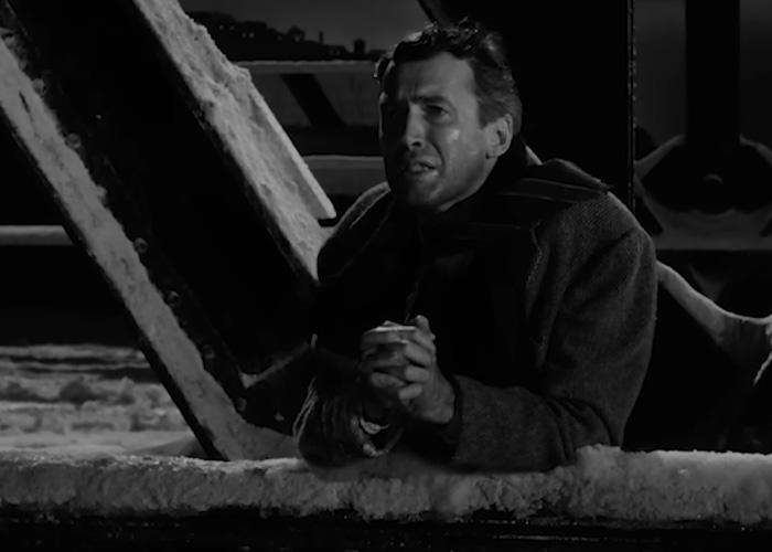 Man in winter coat looking distressed on snow-covered bridge in beloved Christmas classic movie scene.