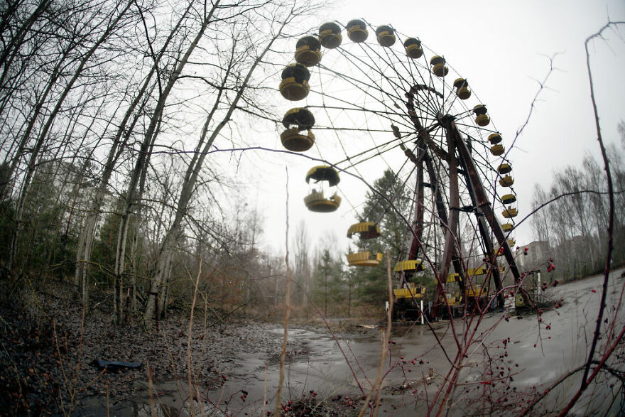 Abandoned Ferris wheel in a desolate forest, representing one of the most dangerous places in the world to visit.