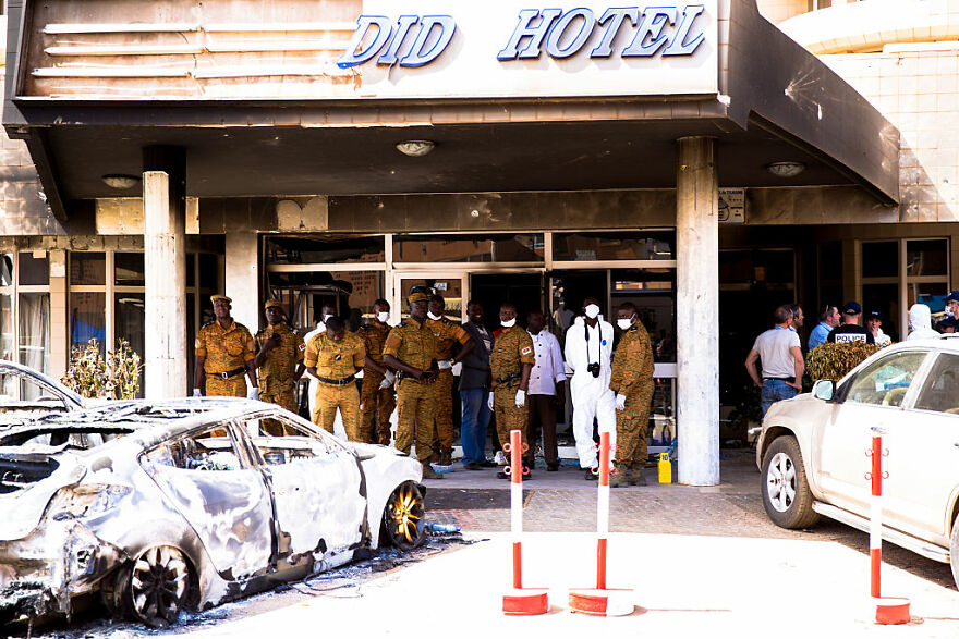 Security personnel and investigators standing outside a damaged hotel in one of the most dangerous places to visit.