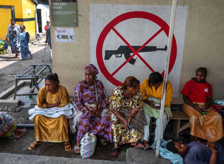 Group of women sitting near a wall with a no guns sign, highlighting one of the most dangerous places in the world to visit.