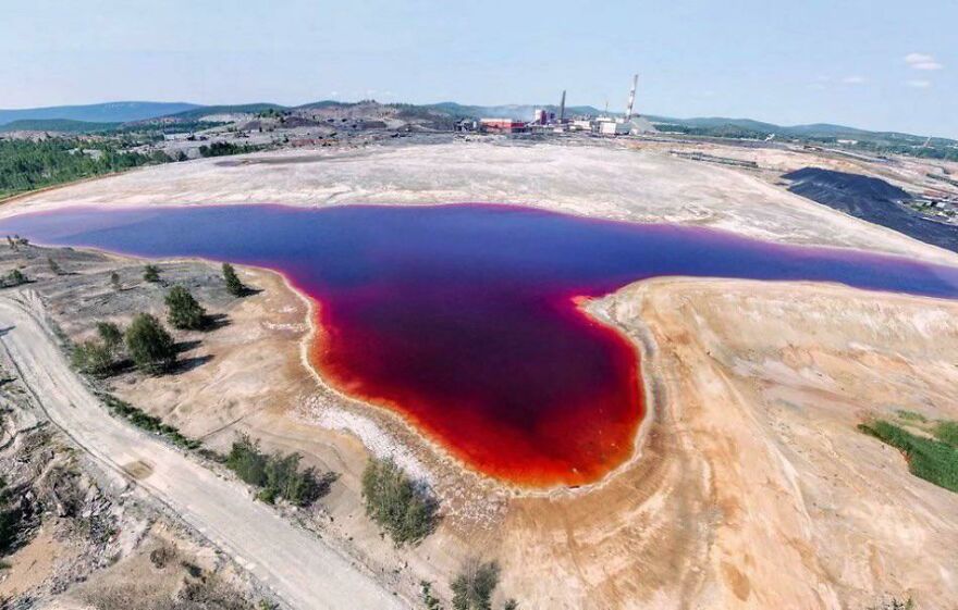 Aerial view of a toxic red lake near an industrial area, one of the most dangerous places in the world to visit.