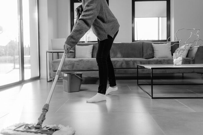 Person mopping the floor in a living room, illustrating calmness in everyday scenarios related to staying calm or losing it.