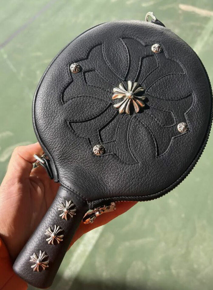 Black leather handbag with metal flower studs in a hand, linked to Timothée Chalamet's red carpet look odd detail Black leather handbag with metal flower studs in a hand, linked to Timothée Chalamet's red carpet look odd detail