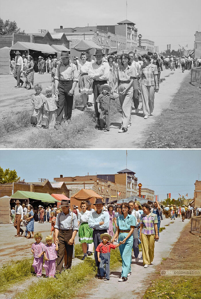 Old black and white photo colorized by artist, showing people walking down a street in a historic setting.