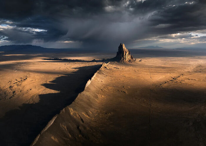 Desert landscape with dramatic clouds and sunlight highlighting rock formations in best nature photography of 2025.