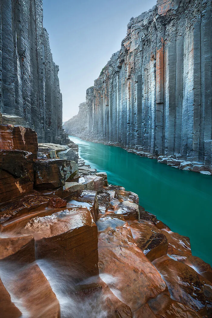 Basalt rock formations and turquoise river flowing through narrow canyon in best nature photography scene.