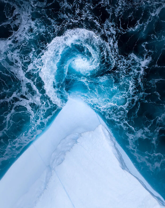 Aerial view of swirling ocean water beside a sharp ice edge, showcasing best nature photography with dramatic natural contrasts.