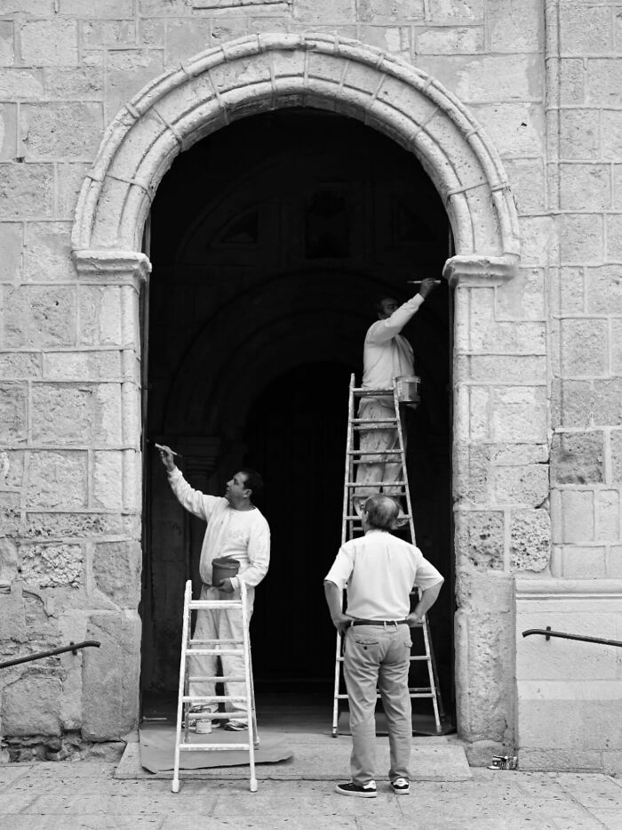 Three men painting a stone archway, capturing street moments that feel like magic in daily life.