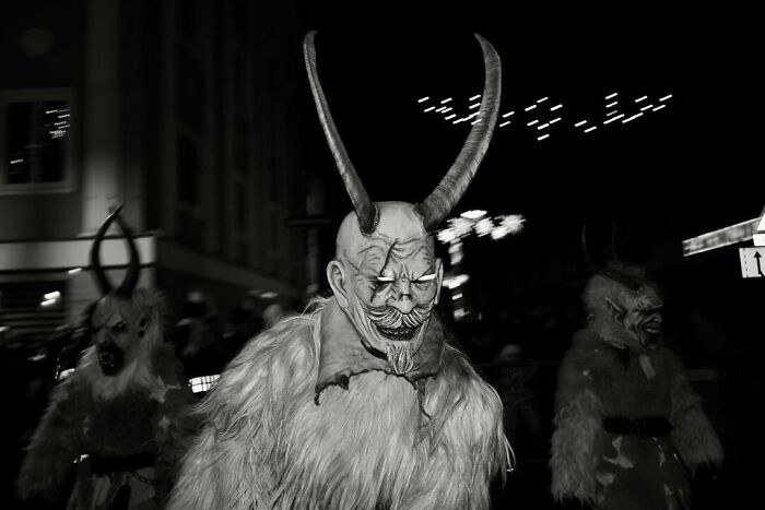 Masked figures with large horns and fur costumes create magical street moments during a nighttime festival event.