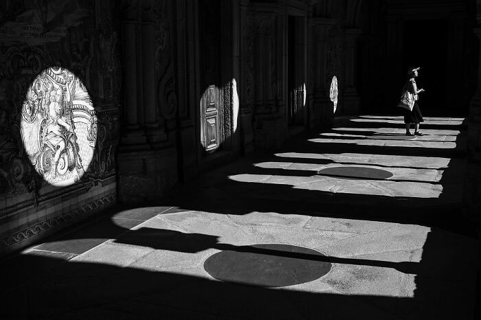 Black and white street scene showing magical light projections on walls and floor, capturing marvels of daily life moments.
