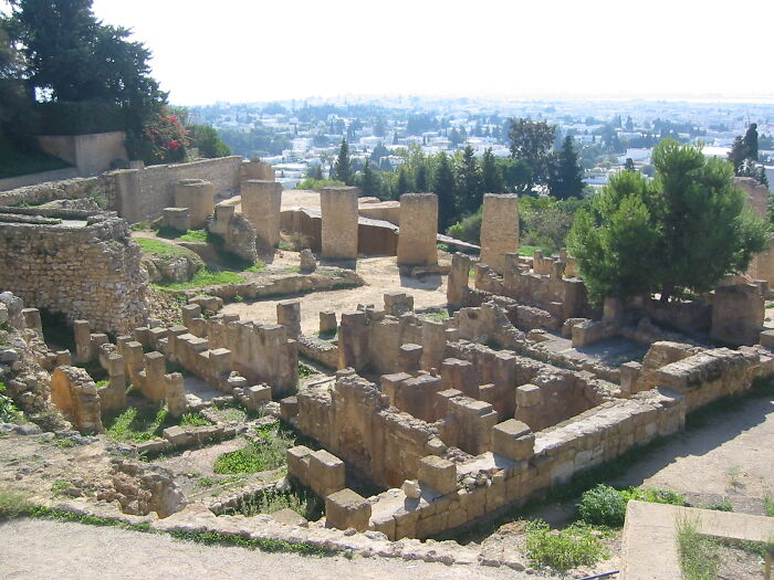 Ancient ruins with stone pillars and walls overlooking a city, illustrating historical facts unknown until recently.