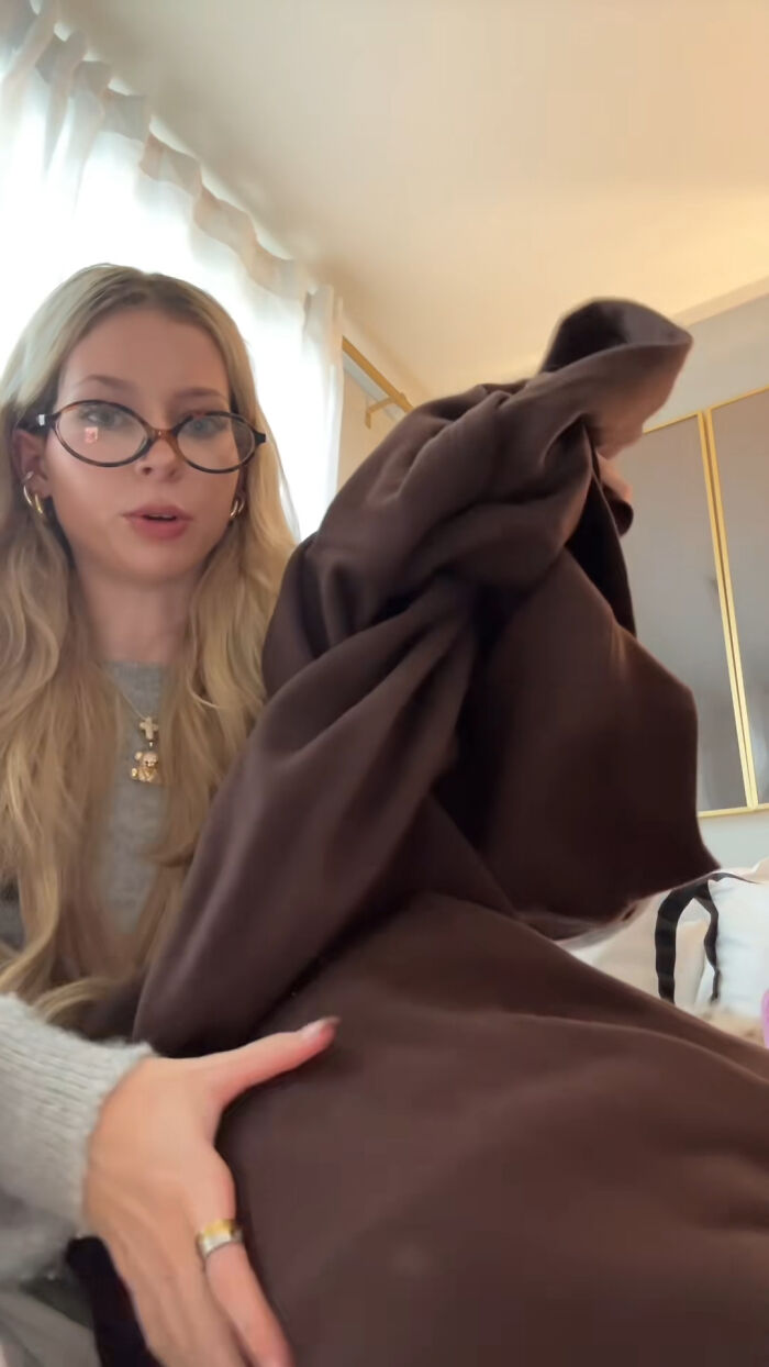 Woman showing a soft brown blanket, one of the top Christmas gifts people highly recommend this holiday season.