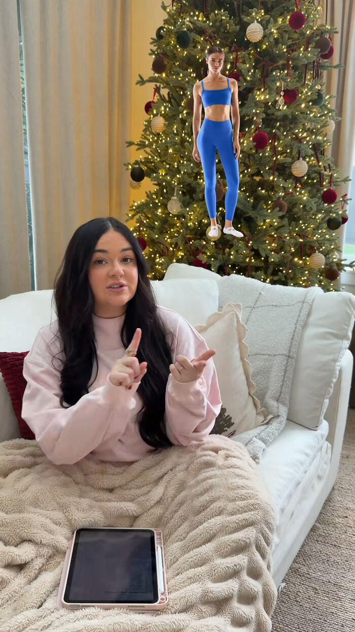 Woman sitting on couch with tablet and Christmas tree behind, discussing popular Christmas gifts recommendations.