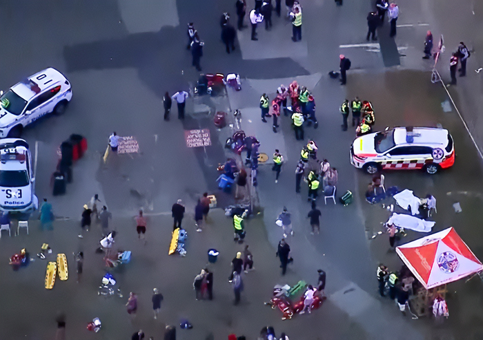 Aerial view of emergency responders and crowd at Bondi Beach after woman takes bullet for 3-year-old during attack.