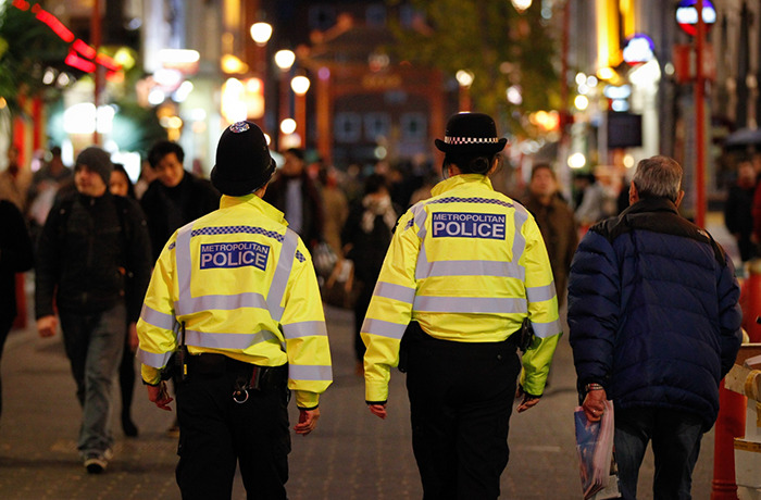 Two metropolitan police officers walking in a crowded urban area investigating wealthy US student behavior after altercation. Two metropolitan police officers walking in a crowded urban area investigating wealthy US student behavior after altercation.