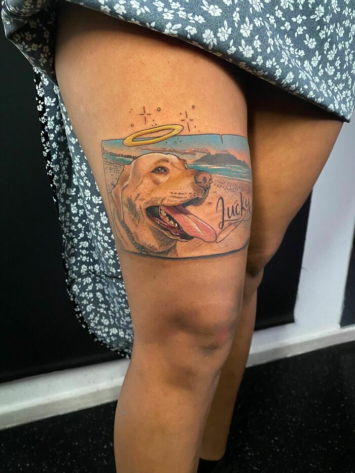 Tattoo tribute on thigh of a dog named Lucky with a halo, capturing memories of pets in a beautiful tattoo design.