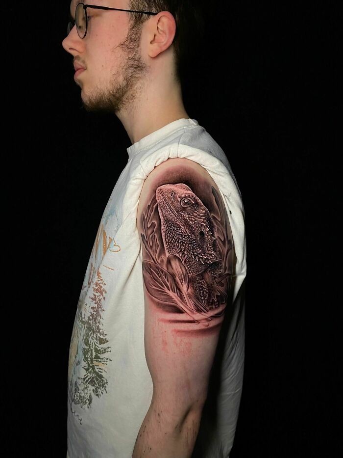 Young man with a detailed pet lizard tattoo on upper arm, a beautiful tribute turning memories into lasting ink art.
