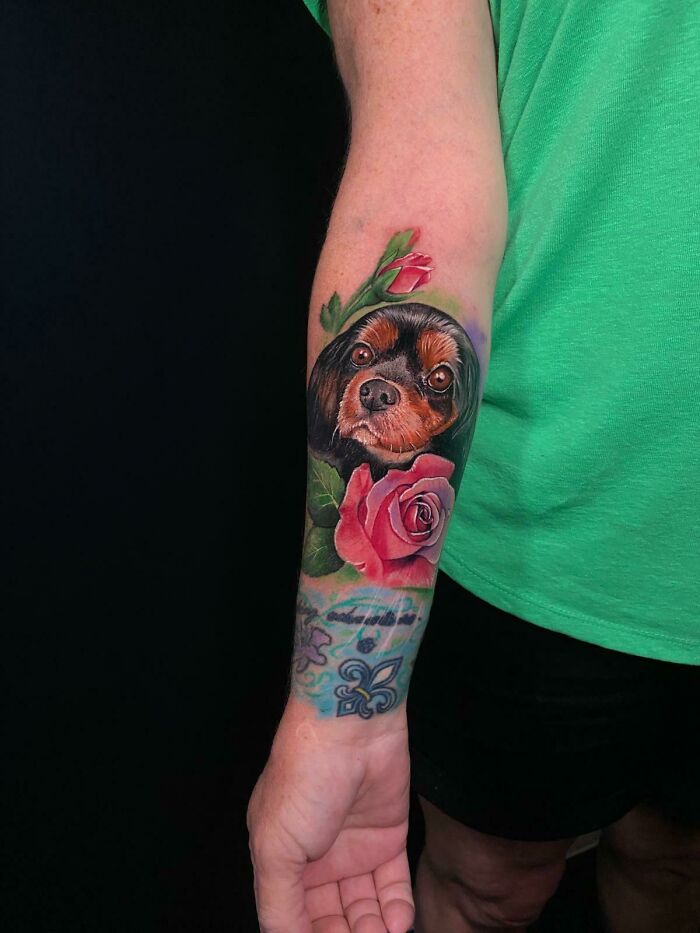 Realistic pet tattoo of a dog's face with a rose flower on a forearm, a beautiful tribute memory tattoo design.