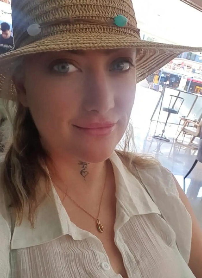 Woman who got veneers in Turkey wearing a straw hat and a necklace, sitting in a bright indoor cafe setting. Woman who got veneers in Turkey wearing a straw hat and a necklace, sitting in a bright indoor cafe setting.