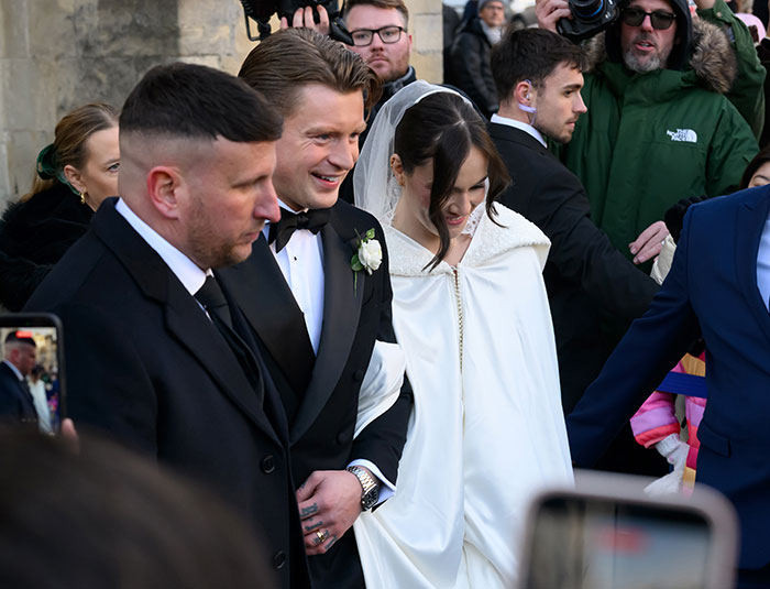 Gordon Ramsay at wedding with daughter and Adam Peaty, surrounded by guests and photographers outside venue.