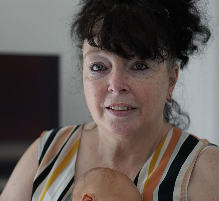 Woman with curly dark hair wearing a striped top, holding a baby, related to Gordon Ramsay wedding speech involving Adam Peaty.