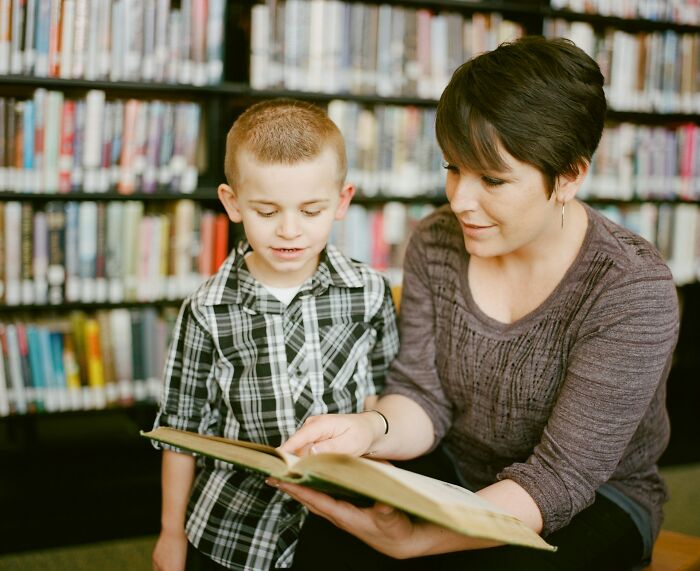 Woman and child reading a book in a library illustrating relatable moments people experienced while working and feeling underpaid.
