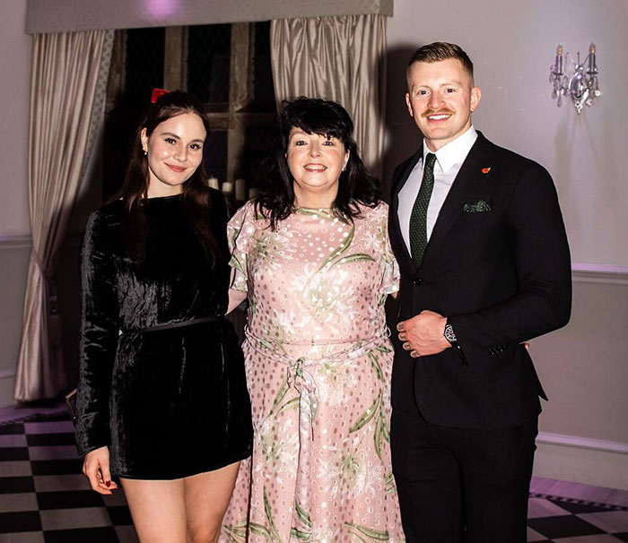 Gordon Ramsay's daughter and Adam Peaty posing with a guest at their wedding event indoors.