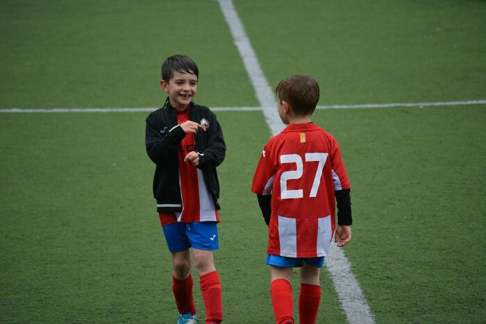 Two young boys wearing soccer uniforms on a field, illustrating signs of still being stuck in their high school era.